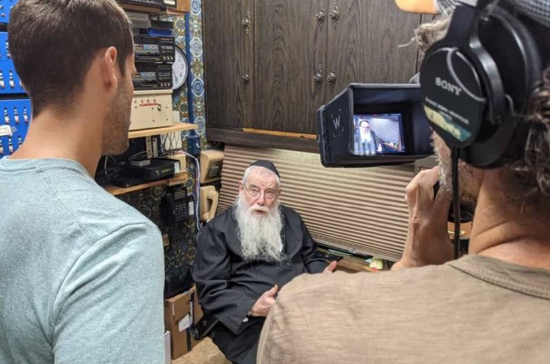 צוות טלוויזיה ברזילי בצילום כתבה בבית חיינו 770. מראיינים את מנהל חדר השידורים הרב חיים ברוך הלברשטאם וחסידים נוספים