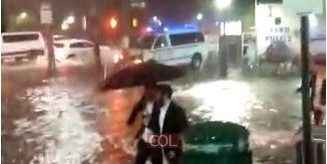עם מטרייה ומגפיים, מים עד הברכיים: בחורים צועדים בשדרת איסטרן פארקווי ממול 770, בכביש שהפך ל'נהר' בעקבות השטפונות העזים מסופת ההוריקן