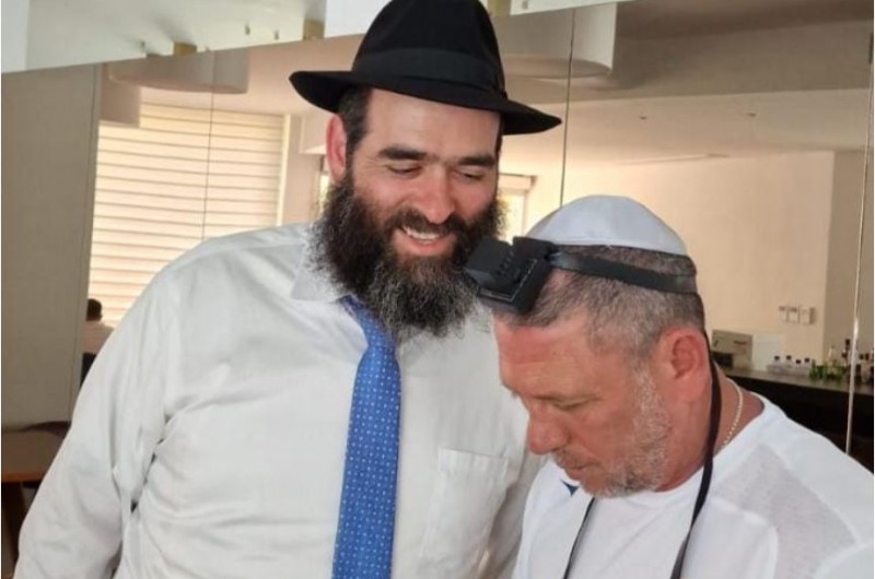 השליח והרב הראשי לקפריסין הרב אריה זאב רסקין, מניח תפילין לידידו ניר קלינגר, מאמן קבוצת הכדורגל הפועל חיפה. מרכז חב