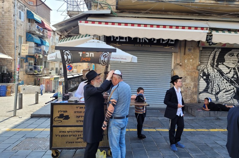 הרב נחמן שפירא, משפיע ישיבת 'אוהלי תורה' בשכונת קראון הייטס הנמצא בישראל, במבצע תפילין בעיצומו של צום תשעה באב, בשוק מחנה יהודה בירושלים